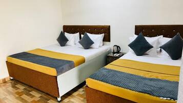 Habitación de hotel con dos camas, cada una con cabecero marrón y colcha amarilla y gris.