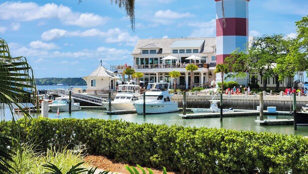 Un puerto deportivo con barcos, un faro y un edificio con terraza.