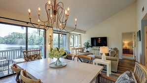Amplia sala de estar con una gran mesa de comedor, asientos cómodos, un televisor y vistas a un lago.