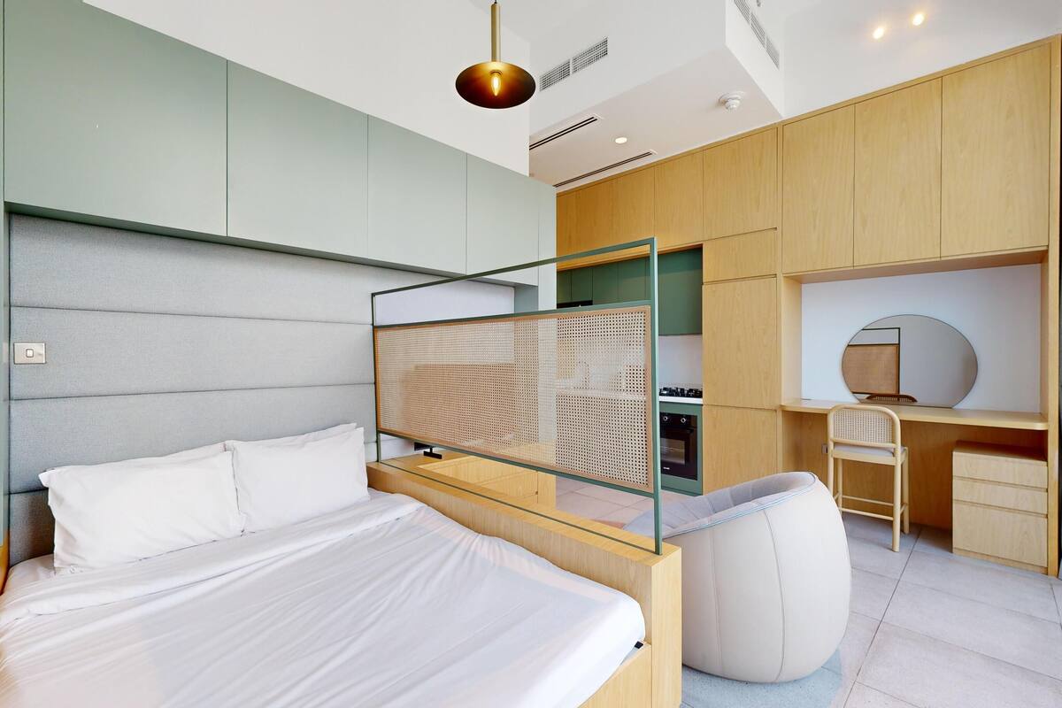 A modern bedroom with a bed, a desk, and a seating area.