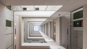 Un interior moderno con un pasillo central que conduce a un tragaluz, flanqueado por divisiones de vidrio e iluminación empotrada.