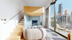 Un interior moderno con una escalera, un televisor de pantalla plana y un balcón con vistas a la ciudad.