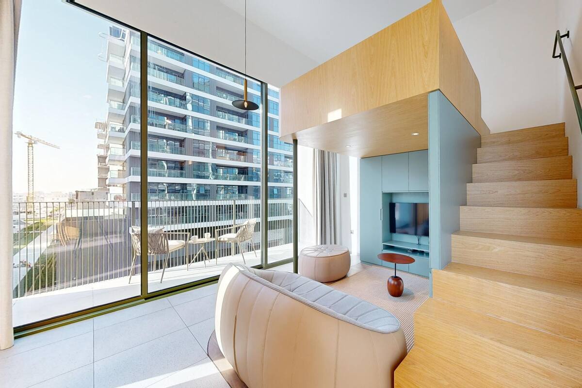 A modern apartment with a large balcony, a sofa, a TV, and a staircase.