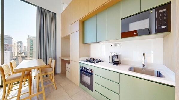 A modern kitchen with a gas stove, coffee maker, and a microwave. There is a dining area with a table and chairs.