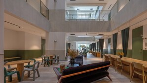 Un espacio interior amplio con diversas opciones de asientos, incluyendo mesas y sillas, y una zona central con un sofá y una mesita de centro.