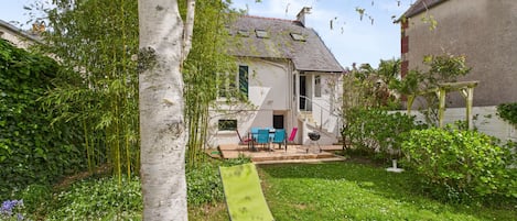 Une maison avec un jardin, une pelouse verdoyante et un mur blanc.