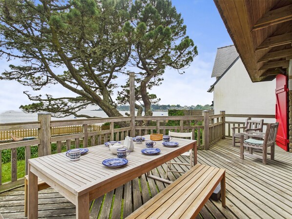 A wooden deck with a table set for dining, overlooking a body of water. - Seaside house with direct beach access for 7 (Bénodet)