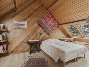 A cozy attic bedroom with wooden walls and a sloped ceiling. It features a bed, a desk, a chair, and a bookshelf. - Seaside house with direct beach access for 7 (Bénodet)