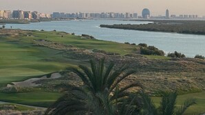 Un campo de golf costero con vistas al horizonte urbano en la distancia.