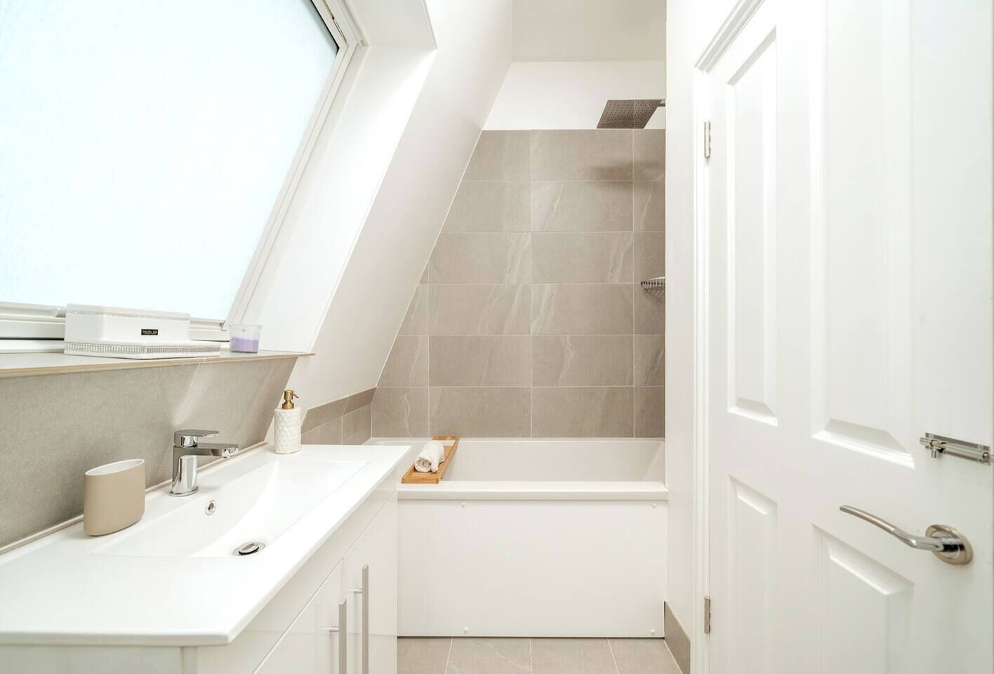 Une salle de bain moderne dotée d’une lucarne, d’une baignoire et d’un meuble-lavabo avec un évier et un porte-serviettes.