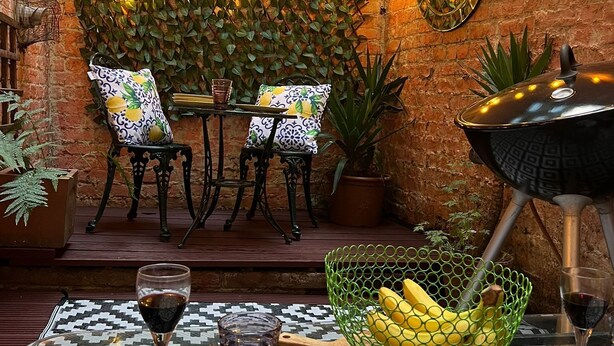 Un área de comedor al aire libre con paredes de ladrillo, luces colgantes y plantas en macetas.