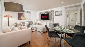 A modern living room with a sofa, coffee table, and dining area set up for a meal.