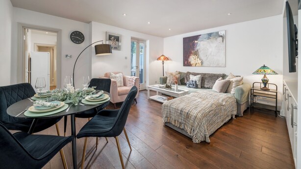 A modern living space with a dining area, a sofa, a bed, and a television.