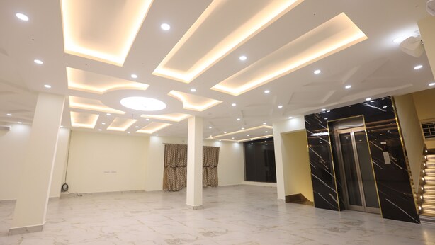A spacious room with a high ceiling featuring recessed lighting and a central circular light fixture. - MM Beach House (Tirupporur)