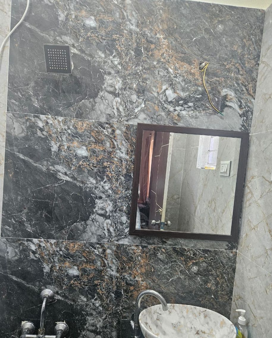 A bathroom with a marble floor, a sink, and a shower.
