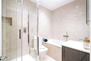 A modern bathroom with a glass-enclosed shower, a white toilet, and a bathtub. - Newly renovated 2-bedroom, 2-bathroom luxury apartment in Earl’s Court/Chelsea, just 8–14 minutes’ walk to the tube. Close to top museums, Royal Albert Hall, and local cafés, pubs, and restaurants — perfect for families, couples, or professionals. (Greater London)