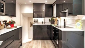 Une cuisine moderne avec des meubles de couleur sombre, un îlot central et une hotte de cuisine en acier inoxydable.