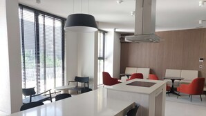 A modern interior with a central white island, black chairs, red chairs, and a beige sofa.