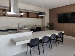 A modern kitchen with a central island, built-in appliances, and a flat-screen TV mounted on the wall.