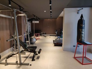 A gym with exercise equipment, a punching bag, and a red stool.