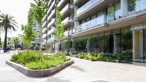A modern building with a glass facade, a landscaped area with plants, and a curved glass feature.