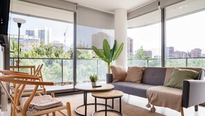 A modern living room with a sofa, chairs, a small table, and a potted plant.