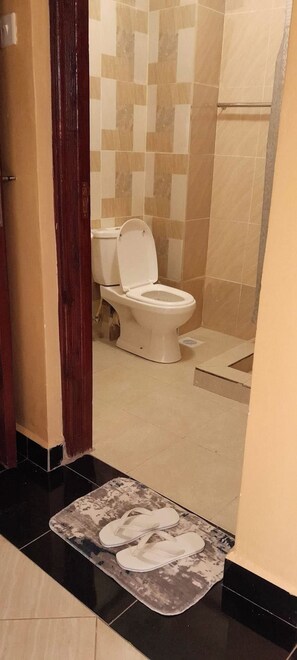 A bathroom with a toilet, tiled walls, and a shower area.