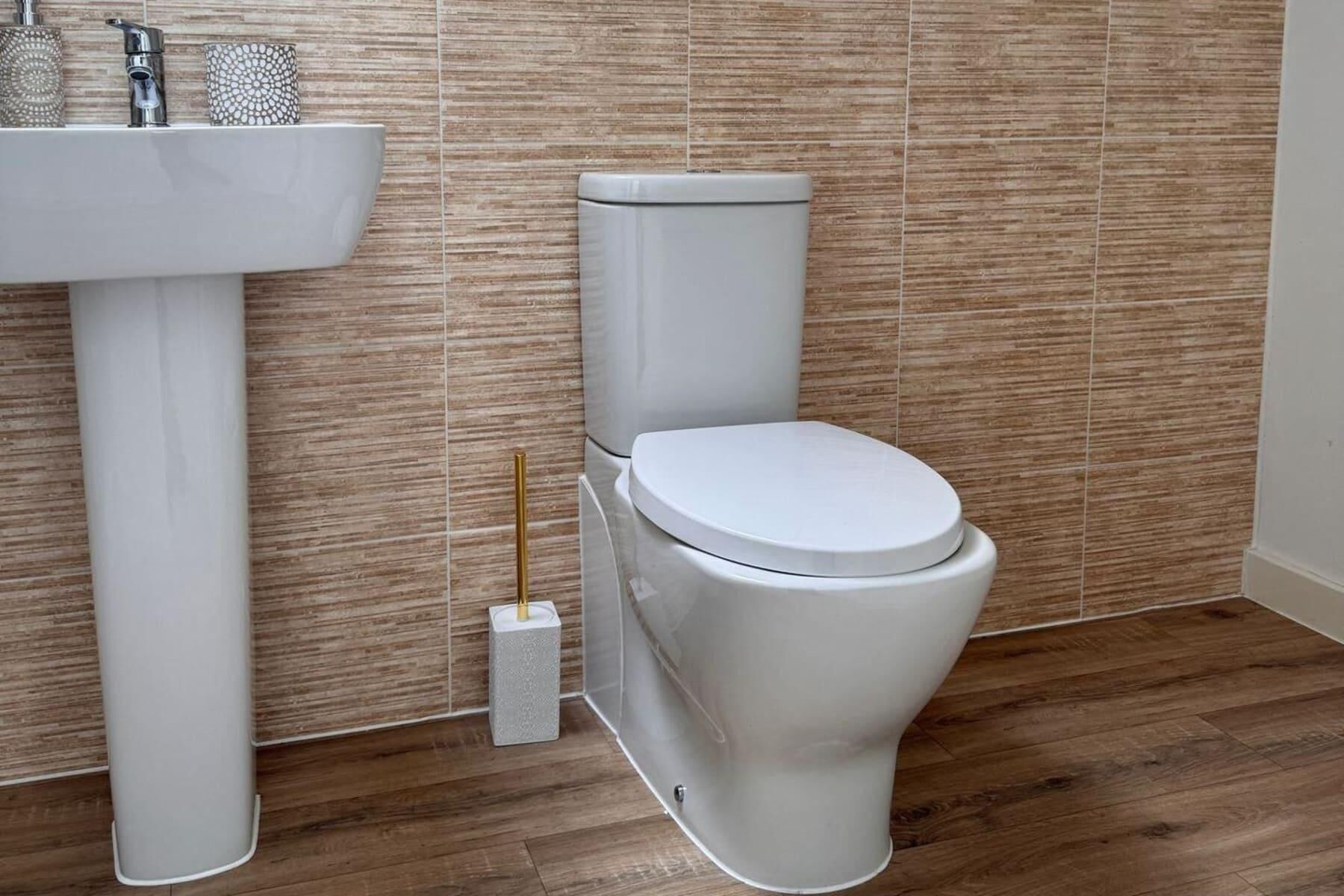 Een badkamer met een wit wastafel, toilet en een kleine prullenbak.
