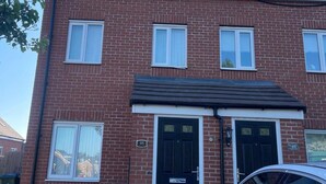 A two-story brick building with a dark roof, numbered 48 and 46, and a car parked in front. - House - Sleeps 6 - Parking (Coventry)