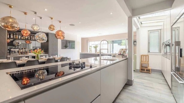 A modern kitchen with a central island, pendant lighting, and a view to the dining area. - Spacious Family Home near Windsor - By Tempstay (Berkshire)