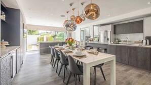 A modern kitchen with a dining area, large windows, and a view of greenery. - Spacious Family Home near Windsor - By Tempstay (Berkshire)