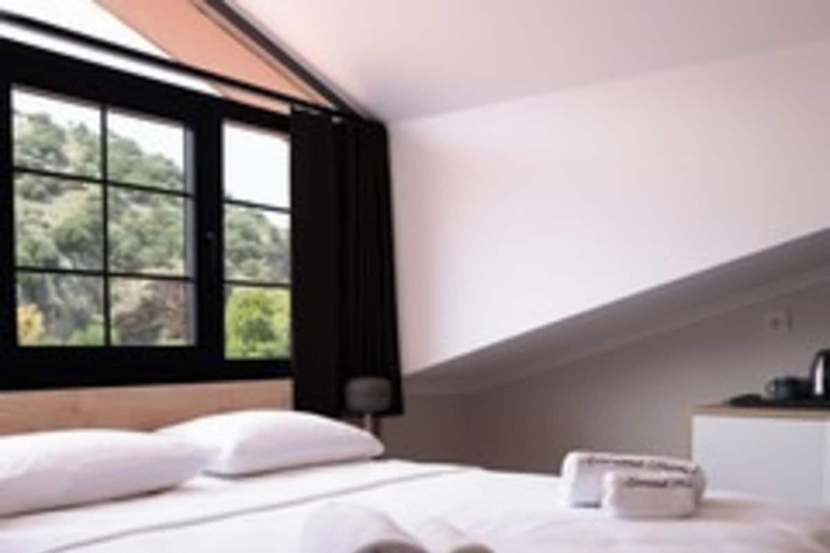 A bedroom with a bed, pillows, a window, and a bedside table.