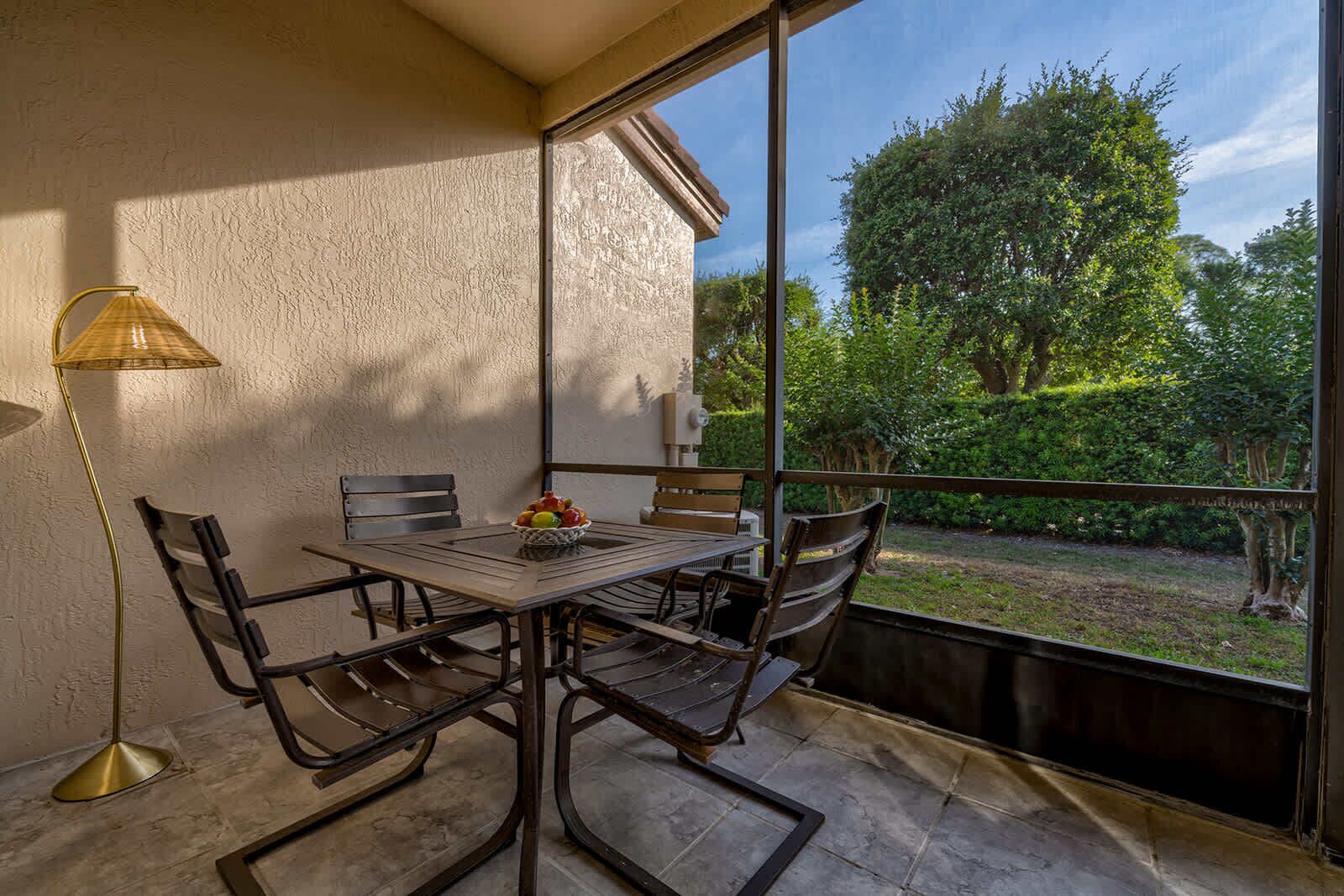 Screened patio with outdoor dining table and garden views