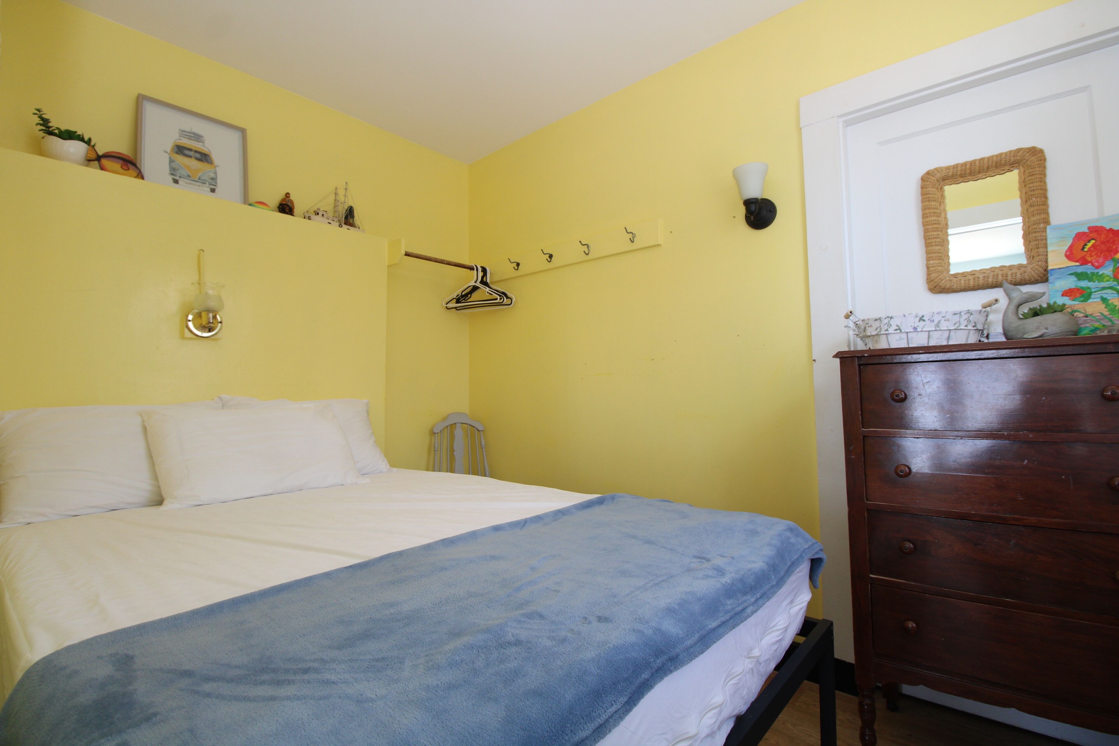 Ein Schlafzimmer mit einem Bett, einem Schminktisch, einem Spiegel und einem Wandhaken für Kleider.
