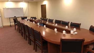 A conference room with a long table, chairs, a whiteboard, and a projector screen.