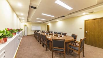 A conference room with a long table, chairs, a whiteboard, and potted plants.