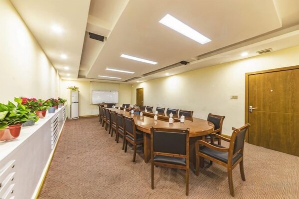A conference room with a long table, chairs, a whiteboard, and potted plants.
