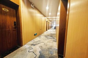 A hotel hallway with wooden doors, carpeted floors, and a corridor leading to a distant end. - Minzu Building Express Hotel (Zhengzhou Zijing Shandong Street Subway Station) (Zhengzhou)