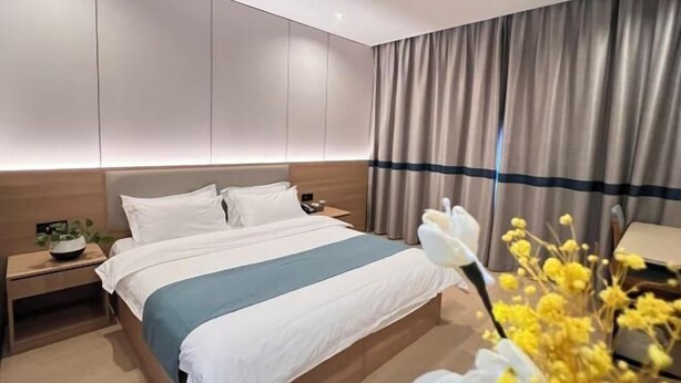 Una camera d'albergo moderna con un letto grande, comodini e vista sulla città.