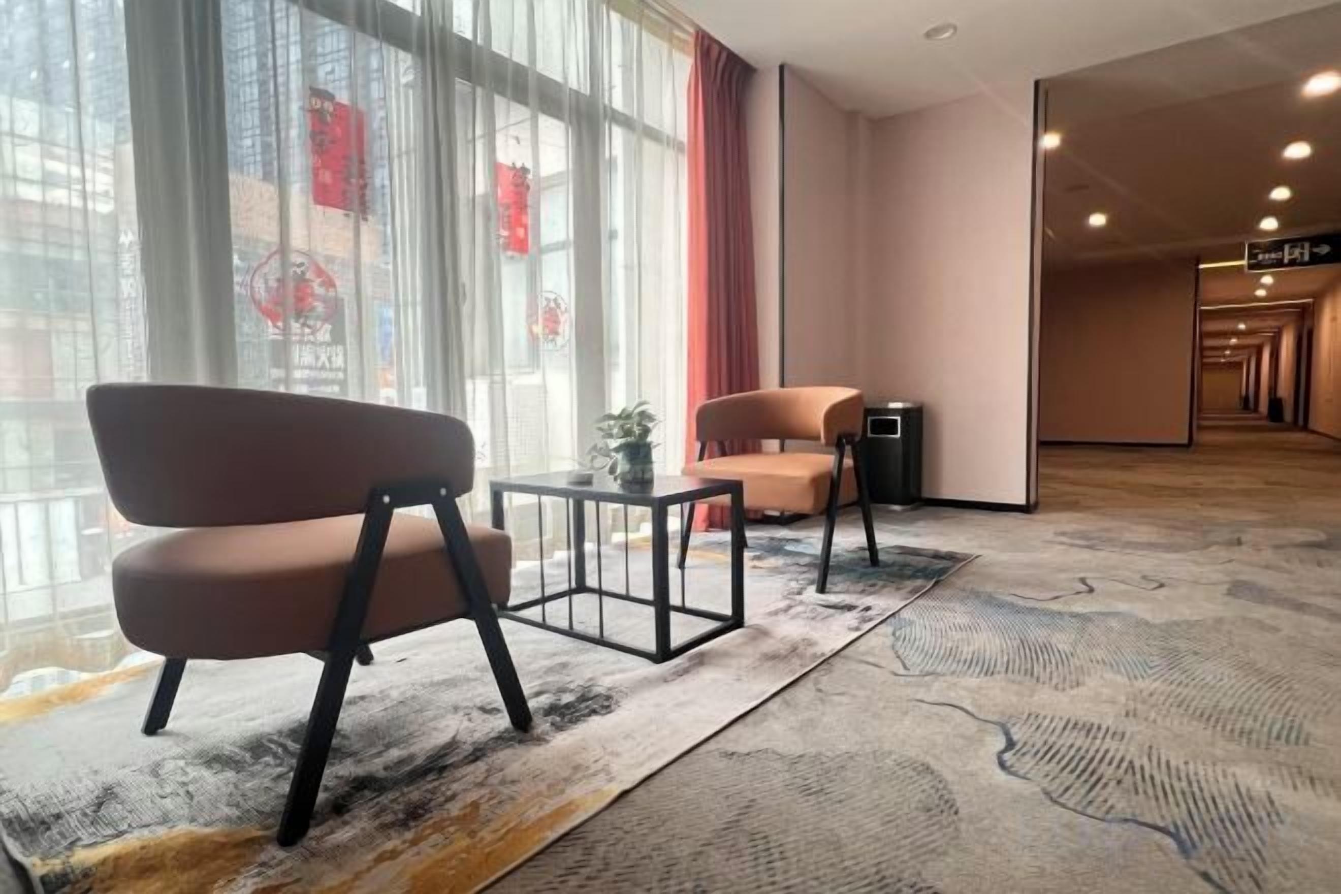 Un hall de hotel con una zona de estar, mostrador de recepción y vistas al exterior a través de amplias ventanas.