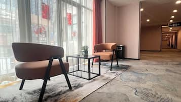 Un hall de hotel con una zona de estar, mostrador de recepción y vistas al exterior a través de amplias ventanas.