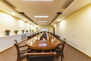 A conference room with a long table, chairs, and potted plants.