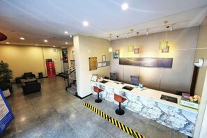 A hotel reception area with a marble counter, a reception desk, and a seating area with chairs. - Minzu Building Express Hotel (Zhengzhou Zijing Shandong Street Subway Station) (Zhengzhou)
