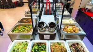 Un buffet con diverse opzioni di cibo, tra cui insalate, noodles e dolci.