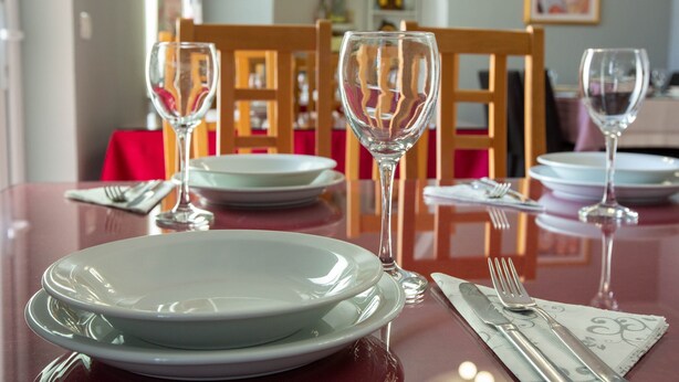 A dining table set with plates, glasses, cutlery, and a napkin. - Pansion Boris Međugorje (Citluk)