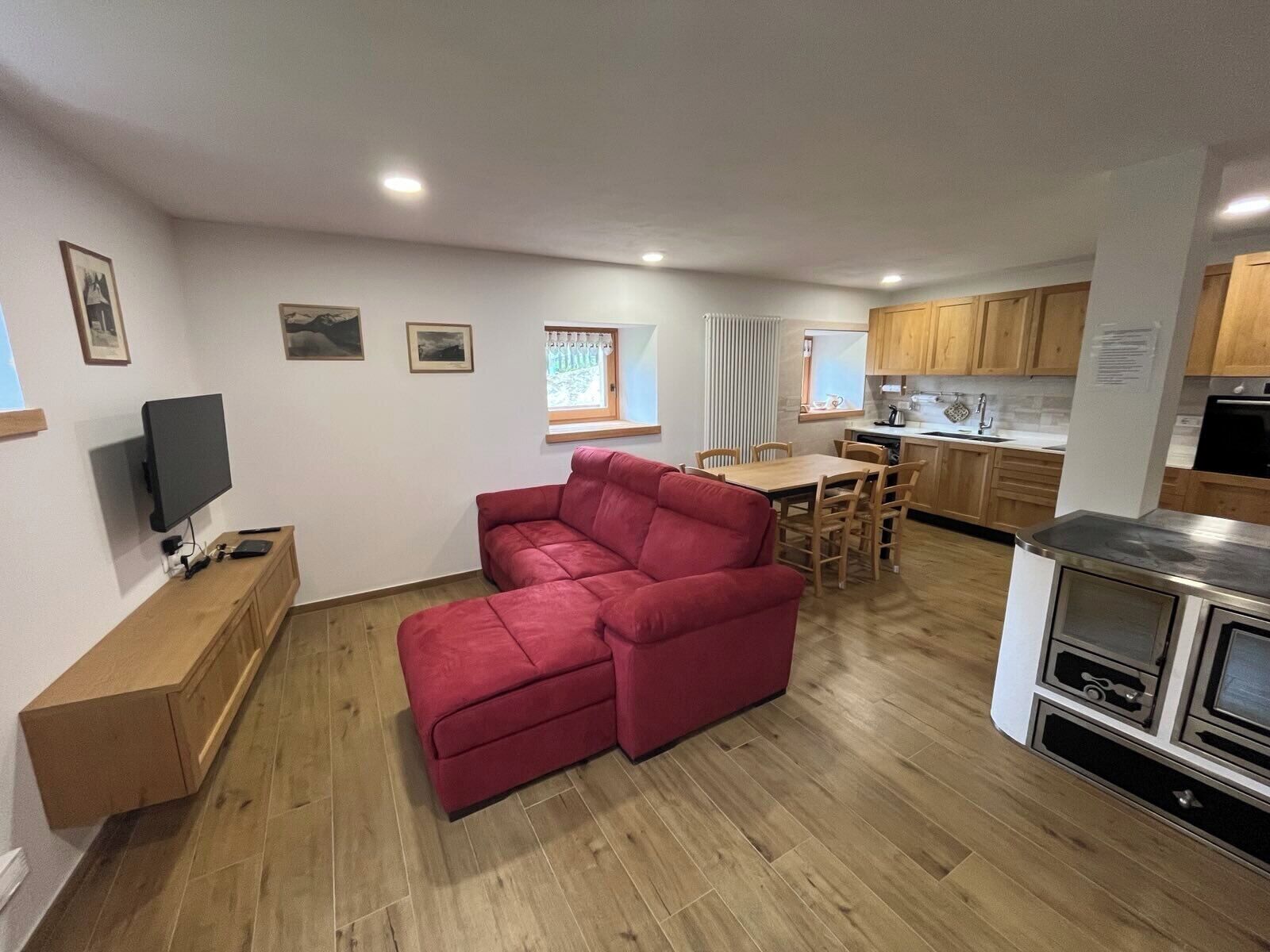 A compact living space with a sofa, a dining table, a kitchen area, and a television.