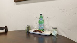 Een eettafel met een fles Pellegrino bruiswater, twee glazen, een kruidenpot en een bord met een chocoladereep.