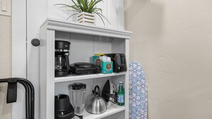 Een witte plank met een koffiezetapparaat, een waterkoker, een blender en een waterfles.