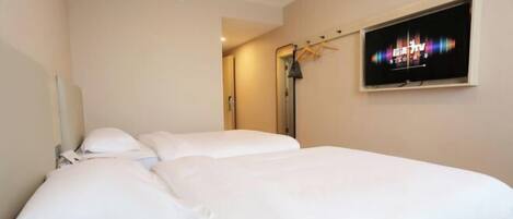 Habitación de hotel con una cama, un televisor en la pared y un espejo.