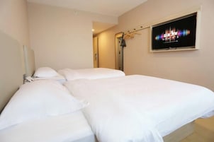 Habitación de hotel con una cama, un televisor en la pared y un espejo.